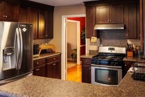 夏洛特In the heart of the QC!的厨房配有木制橱柜和不锈钢冰箱。