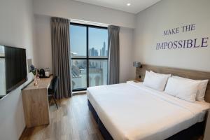 迪拜Kingsgate Canal Hotel by Millennium的一间卧室配有一张床、一张书桌和一个窗户。