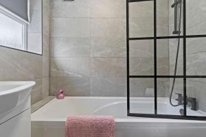 特伦特河畔斯托克Masterson House By RMR Accommodations - NEW - Sleeps 9 - Modern - Parking - Central的带浴缸和玻璃淋浴间的浴室