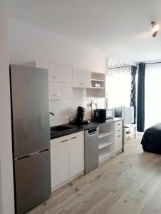 尼萨Apartament Diament 1 - Jezioro Nyskie的厨房配有白色橱柜和不锈钢冰箱