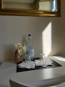科尔托纳Ostello San Marco Cortona的柜台上的一瓶水和两杯眼镜