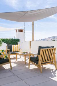 阿尔布费拉Golden Stay - B&B Experience的屋顶上设有两把椅子、一张桌子和一把雨伞