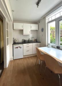 伦敦East Finchley N2 apartment close to Muswell Hill & Alexandra Palace with free parking on-site的厨房配有白色橱柜和桌椅