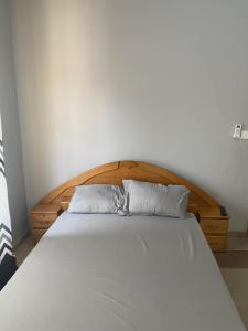 阿克拉Estepona Playa Hostel的一张带木制床头板的床和两个枕头