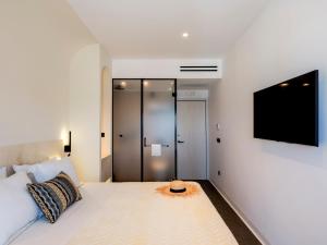 米克诺斯城Yalos Hotel Sunset view Mykonos town private rooms的一间卧室配有一张床,墙上配有电视