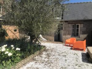 迪南Charmante maisonnette proximité cité médiévale et bords de Rance的一座花园,房子前摆放着橙色椅子