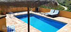 比纽埃拉Los Montes Traditional Casa with private pool的一个带两把椅子和遮阳伞的游泳池