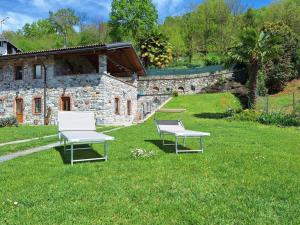韦尔巴尼亚Residenza Jasmine的两把白色椅子坐在石头建筑前面的草上