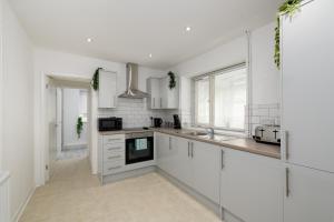 Modern House near Washeries Park的白色的厨房配有白色橱柜和水槽