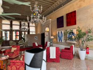 威尼斯鲁奇尼宫酒店的客厅配有红色椅子和吊灯。