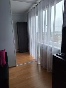 什切青Turkusowa Apartament的客房设有镜子和白色窗帘的窗户