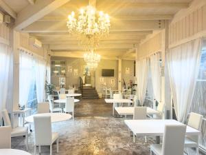 塔尔奎尼亚拉托拉西亚酒店 的餐厅配有白色的桌椅和吊灯