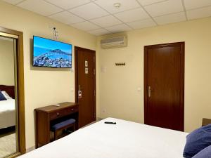 霍斯皮塔勒·德尔英福桑丘酒店的酒店客房设有一张床和墙上的电视