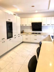 莱基Portland Residence的厨房配有白色橱柜和桌椅