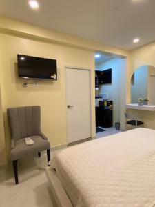 瓜亚基尔Microsuite 4 hermosa y céntrica的一间卧室配有一张床、一把椅子和电视