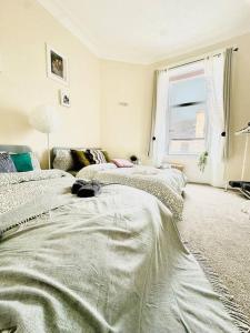邓巴顿Dumbarton cosy home, Loch Lomond的白色的客房设有两张床和窗户。