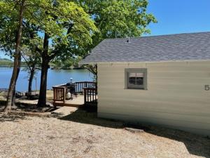 奥沙克湖Lakeshore Fishing Cabin 5, dock, boat slip and firepit area的水体旁边的白色小建筑