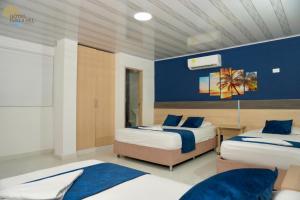 圣玛尔塔Hotel Perla del Caribe的一间卧室设有两张床和蓝色的墙壁