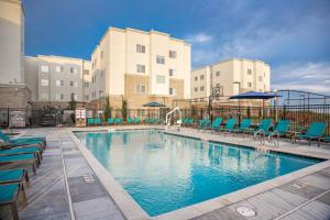 圣何塞Residence Inn by Marriott San Jose North/Silicon Valley的一座带蓝色椅子的游泳池和一座建筑