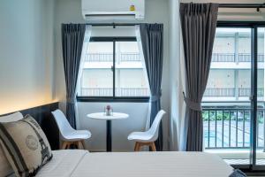 曼谷College Haus Rangnam的酒店客房带一张床、一张桌子和椅子