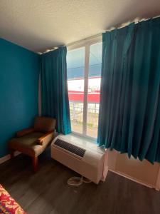 什里夫波特Clover Inn and Suites的一间卧室设有窗户,配有蓝色窗帘和风扇