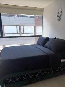 波哥大Moderno apartamento 820-1的一张黑色的床,位于一个设有大窗户的房间
