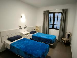 大加那利岛拉斯帕尔马斯Turina House - 3 habitaciones的客房设有两张床、一把椅子和窗户。
