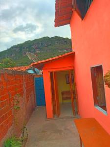 穆库热Casa Rainha da Serra的橙色的建筑,设有一扇带长凳的开放式门