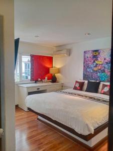 芭东海滩百佛生活公寓的一间卧室配有一张带书桌和绘画的床。