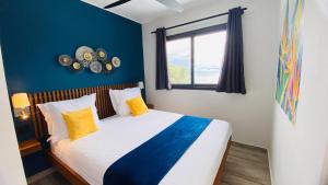 贝岛BLUE VELVET的一间卧室配有一张带黄色枕头的床和一扇窗户