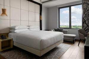 拉各斯Lagos Marriott Hotel Ikeja的卧室配有一张白色大床和一把椅子