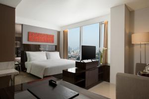 雅加达萨提卡高级哈亚乌鲁雅加达酒店的一间卧室配有一张床和一张书桌及电视
