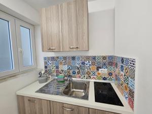 卡普里La Bomboniera的厨房配有水槽和瓷砖墙壁