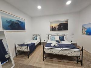 卡普里La Bomboniera的一间卧室设有两张床,墙上挂有绘画作品