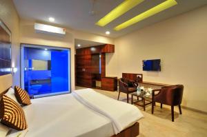 JalālpurHare Krishna Hotel的一间卧室配有一张床、一张书桌和一台电视。