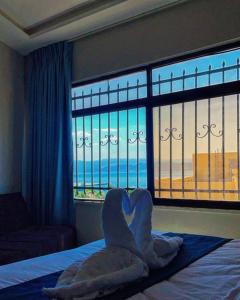 亚喀巴Aladnan hotel的卧室配有带窗户的床上心形毛巾