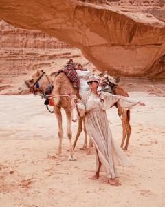 瓦迪拉姆Hasan Zawaideh Camp的站在沙漠骆驼旁的女人