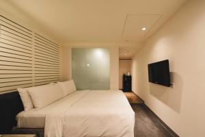 台北二十轮旅店西门町馆的卧室配有白色的床和平面电视。