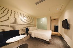 台北二十轮旅店西门町馆的一间卧室配有一张床、一张沙发和一台电视