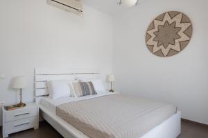 普拉提伊亚洛斯西弗诺斯伊里尼公寓式酒店的白色的卧室配有一张床和墙上的时钟