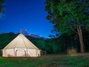 布永Lodg'ing Nature Camp Ardennes NEW 2024的绿地中的白色帐篷,有树