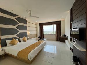巴罗达Hotel Grand Darshan Vadodara的一间卧室配有一张大床和电视