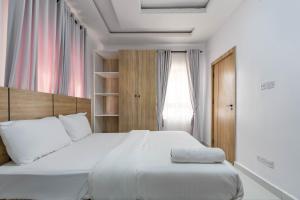 拉各斯Firenze Apartments Lekki的卧室设有一张白色大床和一扇窗户。
