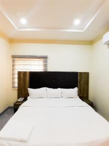 RubuchiCome Inn Hotel的一间卧室配有一张白色大床和黑色床头板