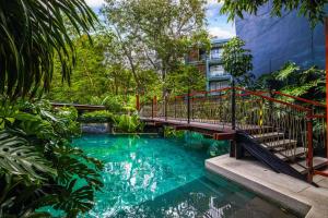芭东海滩普吉岛自然-YYC旅游优选酒店 Phuket Nature-YYC Travel Preferred Hotel的一座桥,一座有树木的游泳池,一座建筑