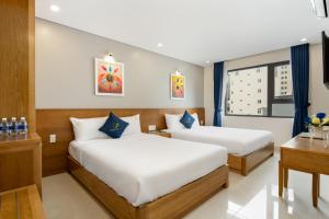 岘港CODI SEA Hotel & Travel的酒店客房配有两张床和一张书桌