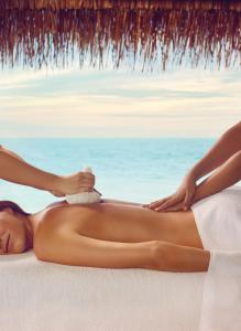 南马累环礁Taj Exotica Resort & Spa的一位有按摩师躺在海滩上的女人