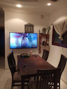 沙迦Family Room In Sharjah的餐桌、椅子和墙上的电视