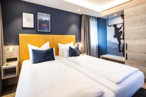 柯尼希斯湖畔舍瑙国王湖酒店的卧室配有带蓝色枕头的大型白色床