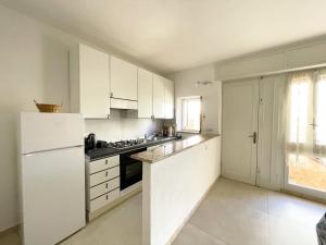 马达莱纳Nuovo Appartamento Ristrutturato in Corte Interna的厨房配有白色橱柜和白色冰箱。